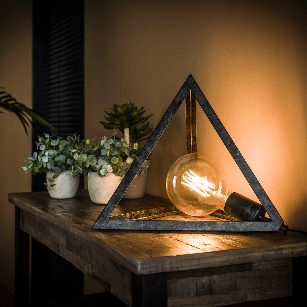 Pyramideformet bordlampe i patineret sort metal.